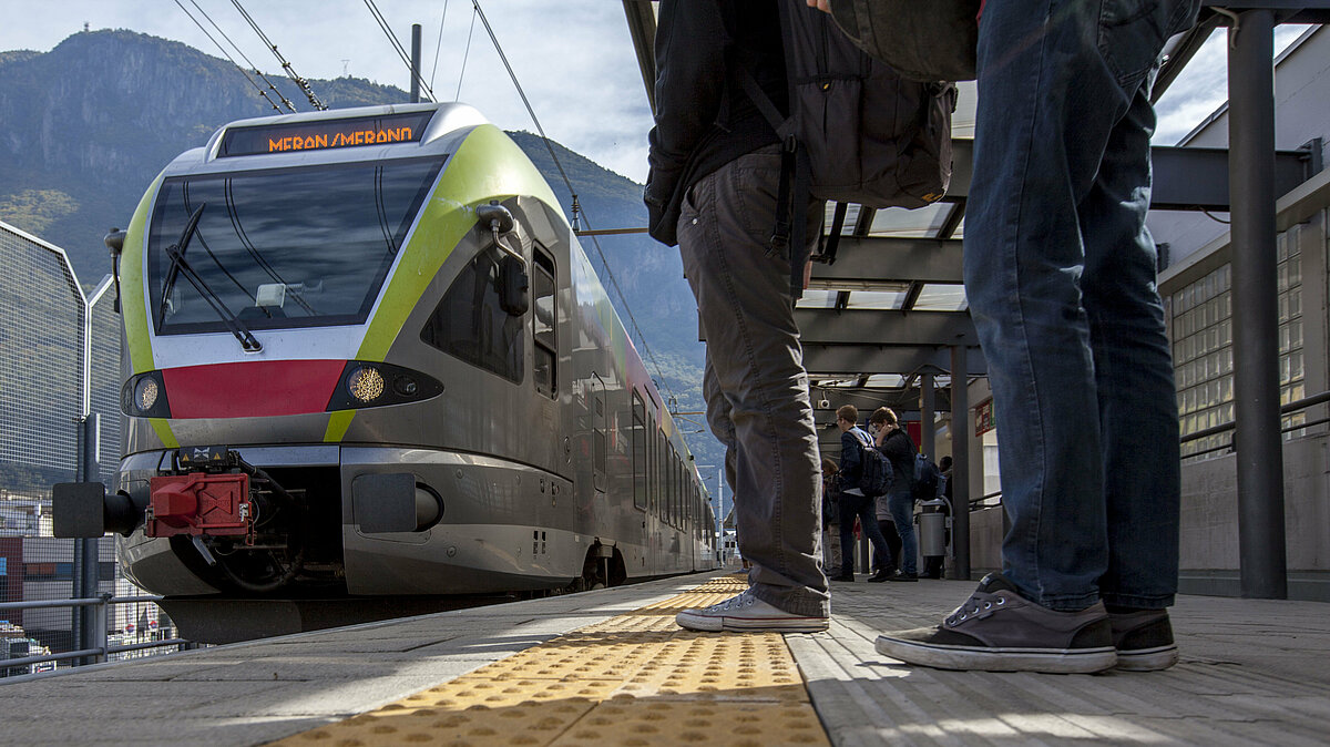 Persone e studenti aspettano il treno in stazione. Il treno sta arrivando.
